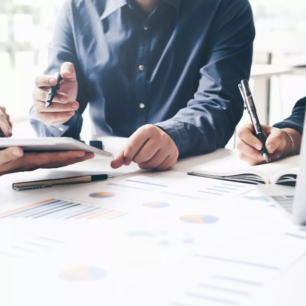 Businesspeople collaborating, reviewing data on a tablet and documents.